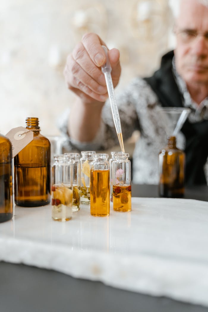 A person blends aromatic essences using a dropper for bespoke fragrances, emphasizing artisanal craftsmanship.